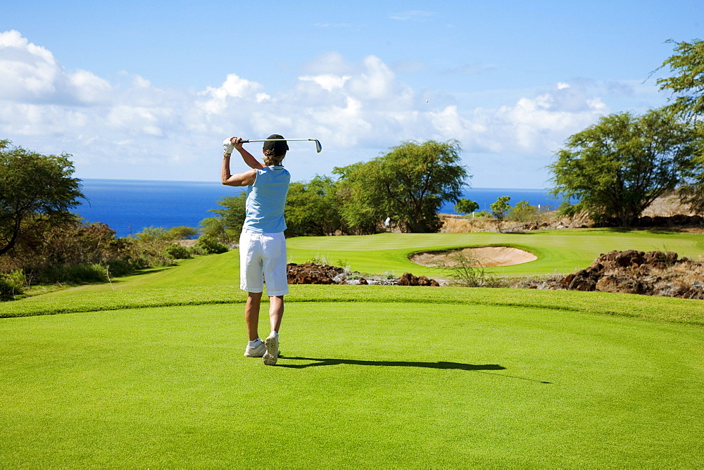 Hawaii, Lanai, Woman hitting a tee shot on The Challenge at Manele golf course.