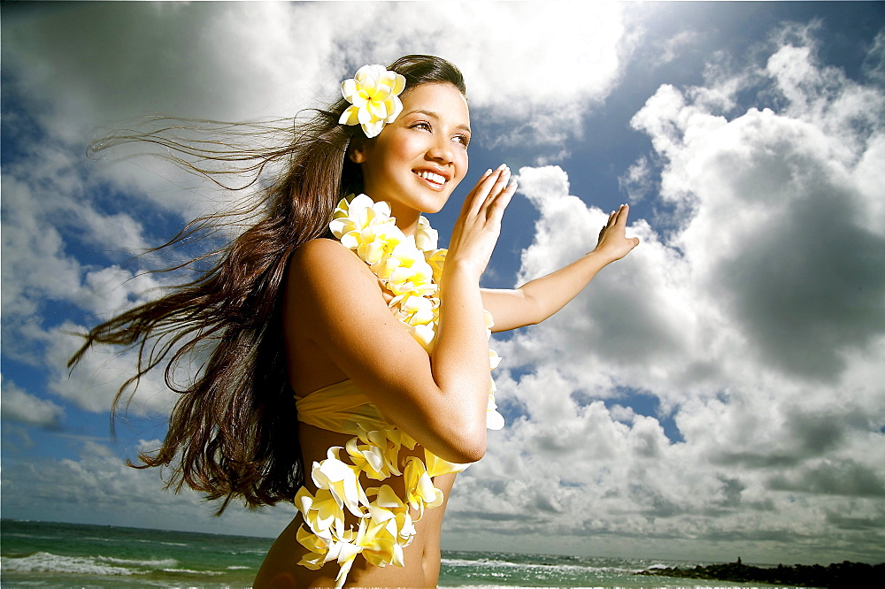 Hawaii, Kauai, Kealia, Beautiful Hawaiian girl dancing hula on ocean shoreline.