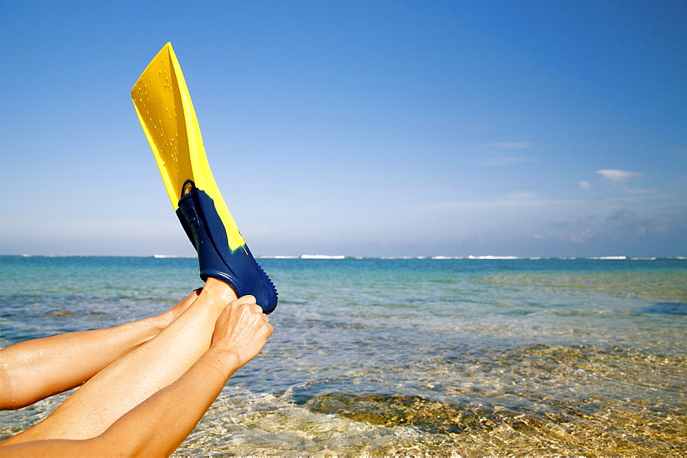 Hawaii, Kauai, Tunnels beach, A woman wearing yellow and blue fins on beach.