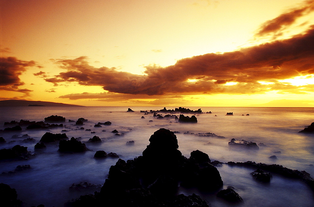 Hawaii, Maui, Sunset over rocky beach, Kahoolawe and Molokini islands in distance, Long exposure.