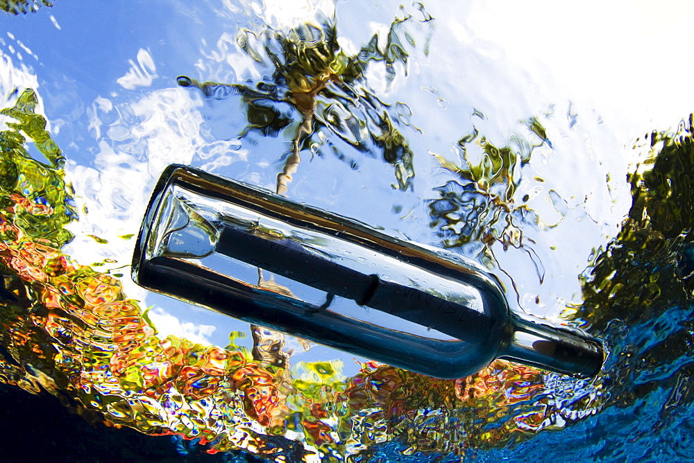 Hawaii, Underwater view of a message in a bottle.