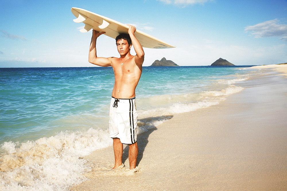 Hawaii, Oahu, young man at the beach with surfboard.