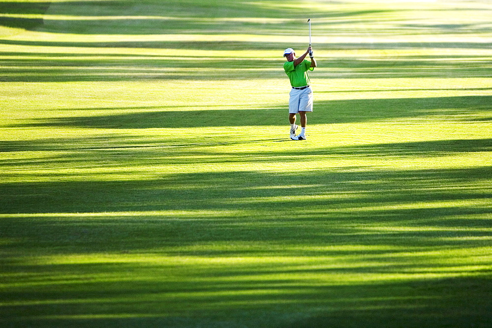 Hawaii, Maui, Male golfer swinging golf club at the Maui Country Club course.