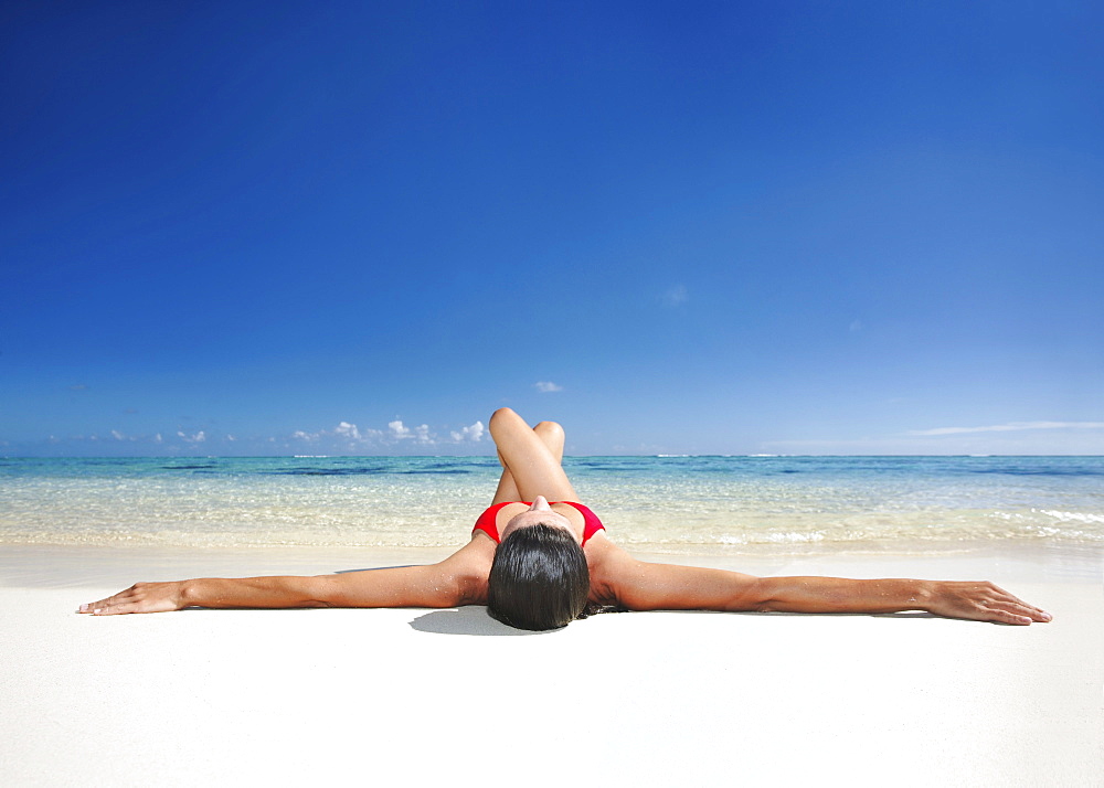 Hawaii, Woman laying on the beach in remote tropical location.