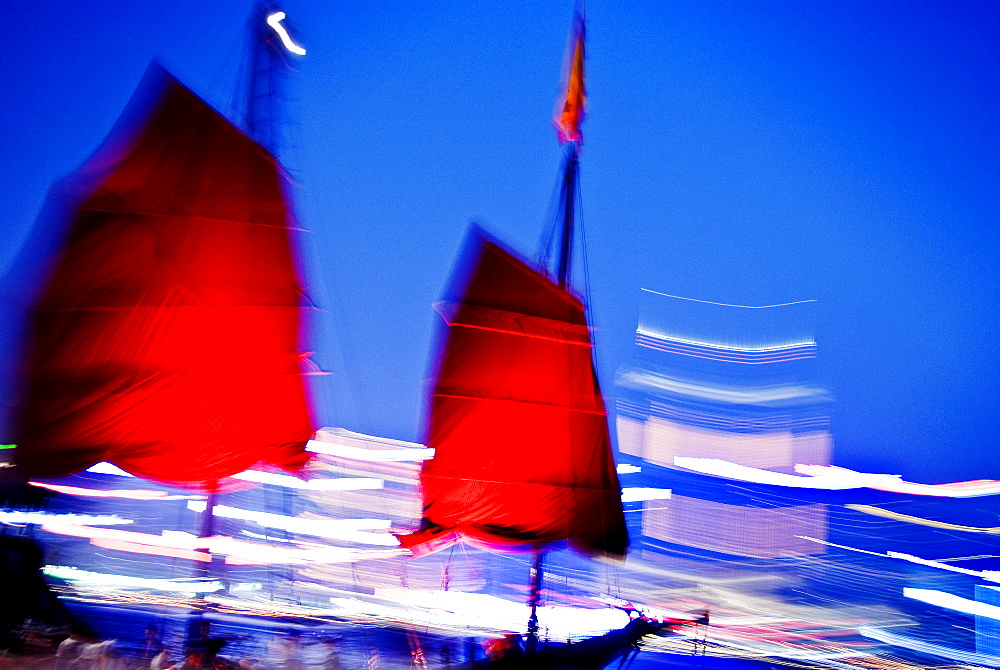 Hong Kong, Tsim Sha Tsui K, A red sailed chinese junk boat passes in front of Hong Kong Island.