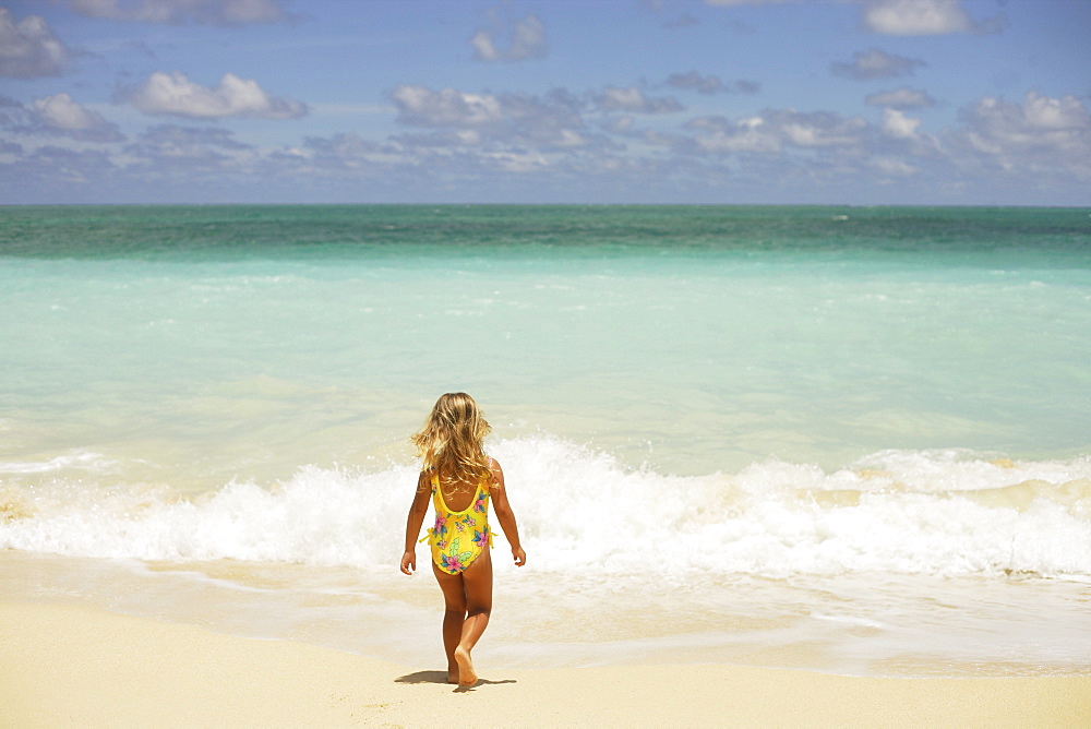 Hawaii, Oahu, little girl walking away on beach.