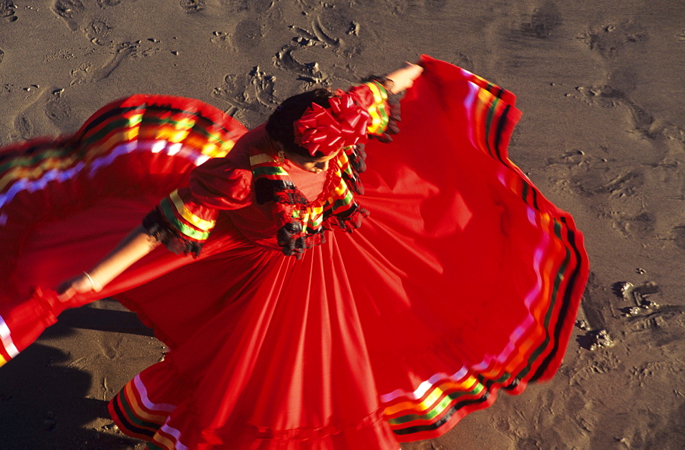 Mexico, View from above of woman in red dress dancing on sand.