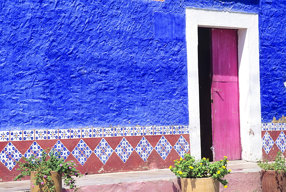 Mexico, Contrasting colorful restaurant wall with hand painted trimming.