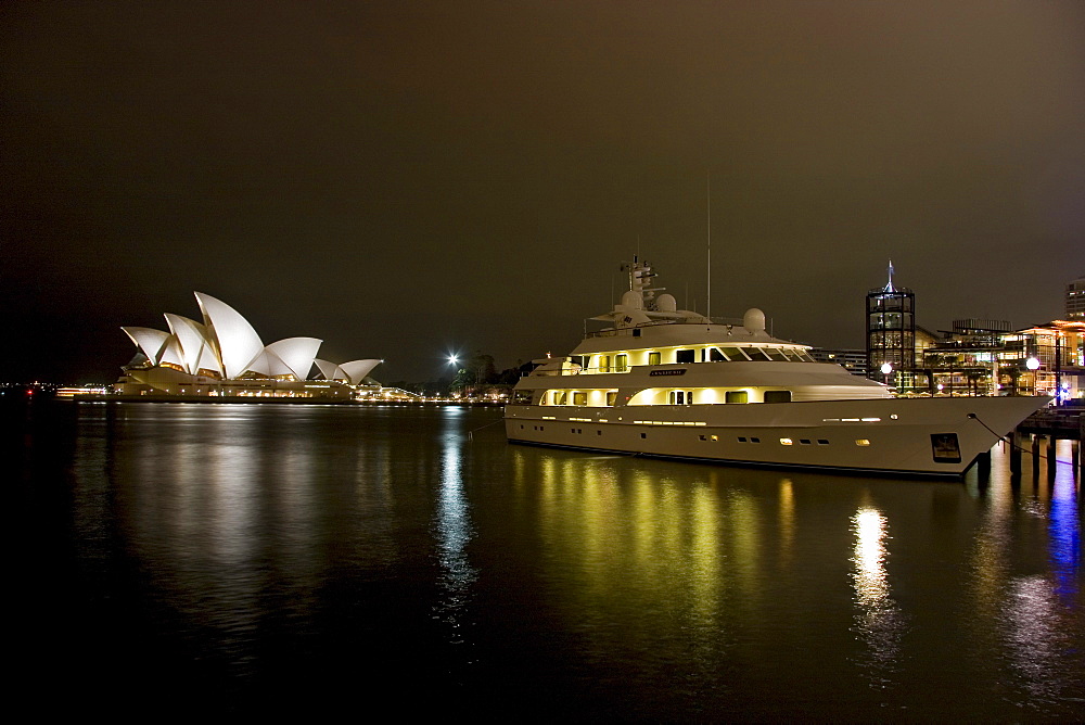 Australia, Sydney, A night scene looking across Sydney Harbor to the iconic Opera House, large yacht in foreground.