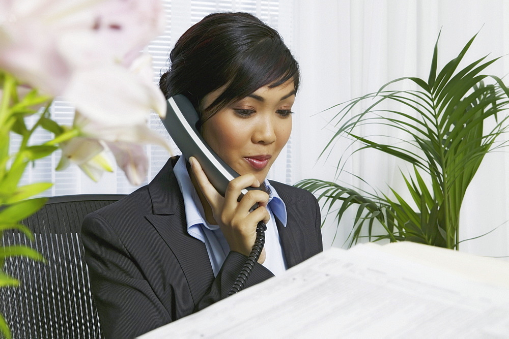 Asian businesswoman in office on phone.