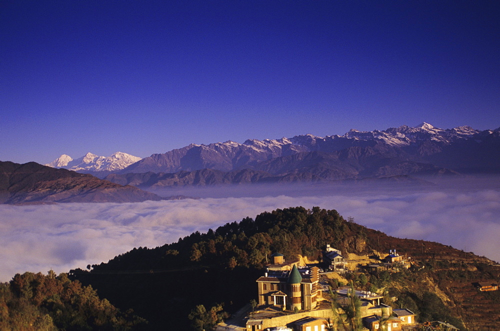 Nepal, Nagarkot, overview of Niva Lodge on hillside, cloud line and Himalayan range in background.