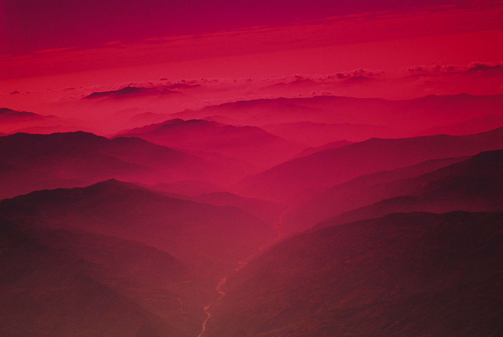 Nepal, Kathmandu Valley, river flowing between mountains at sunset, red foggy glow.