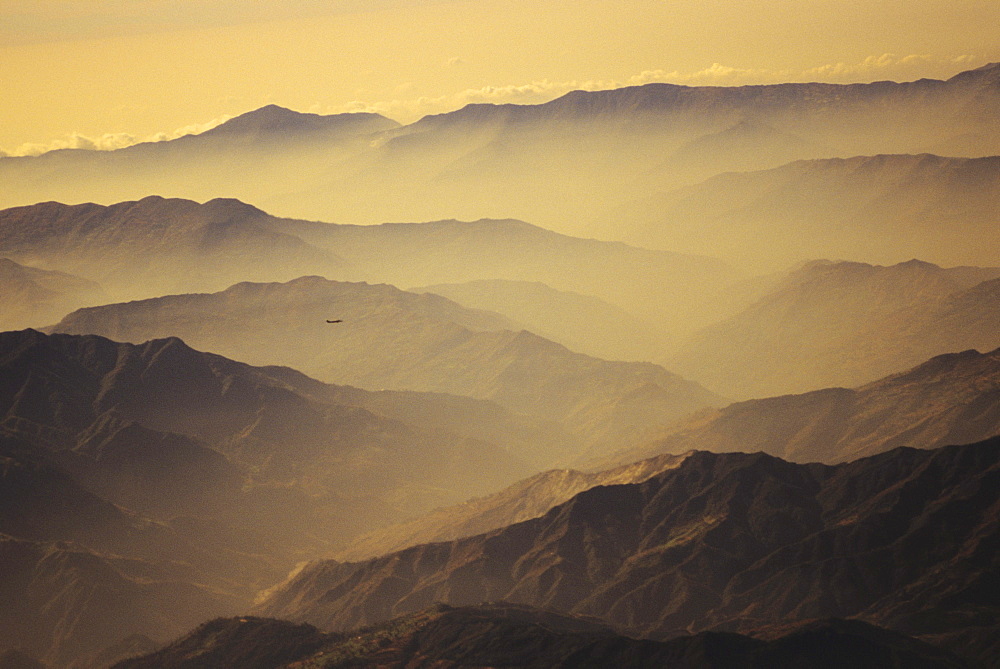 Nepal, Kathmandu Valley, overhead view of hill tops silhouetted among yellow haze and sky.