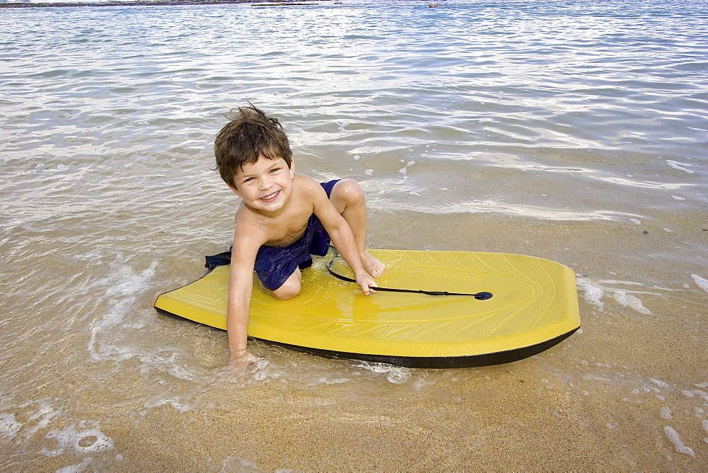 Hawaii, Maui, Spreckelsville, Baby Beach, Young boy playing in the water on a boogieboard