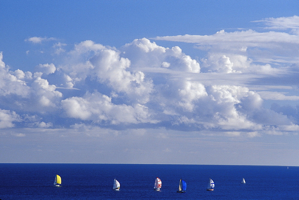 Clouds in sky overlooking ocean with sailboats in distance.