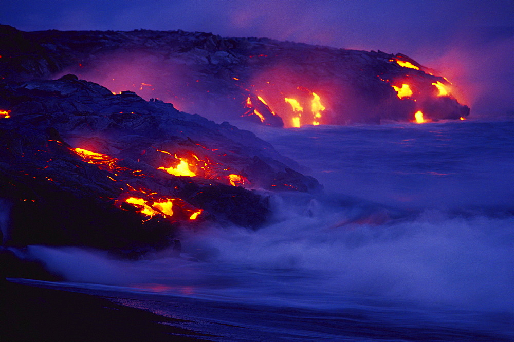 Hawaii, Big Island, Hawaii Volcanoes National Park, Lava flows into ocean at night, creating a purple mist.