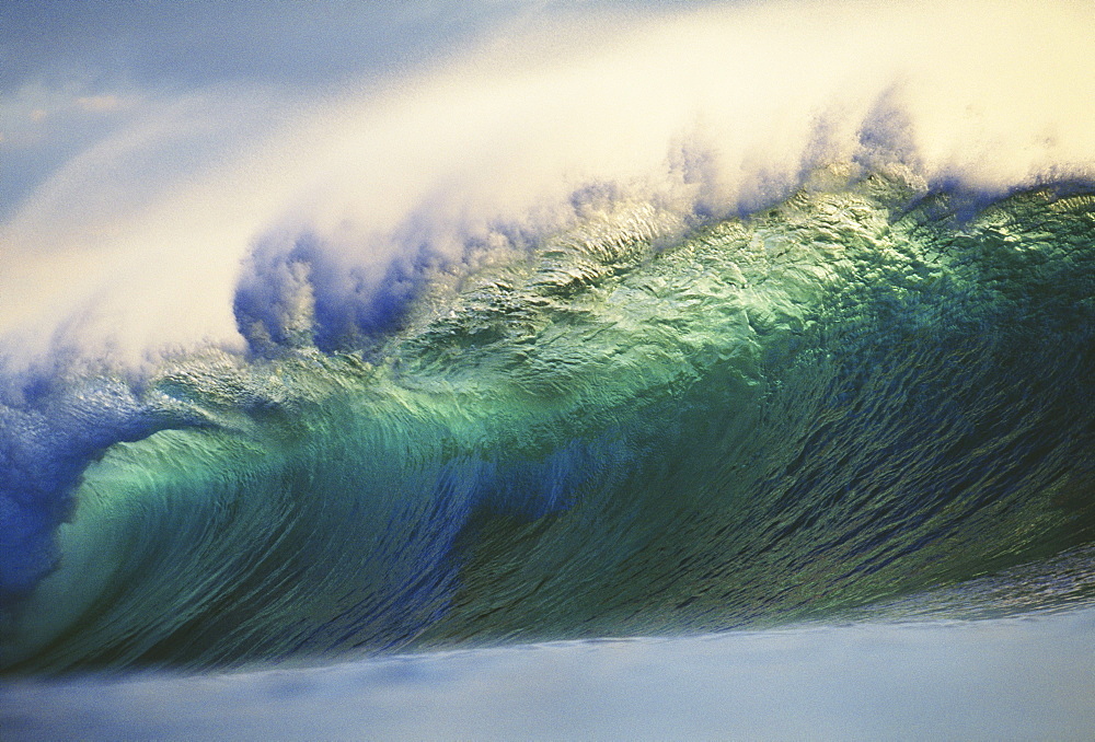 Hawaii, Oahu, North Shore; large green wave about to curl with mist blowing off tip