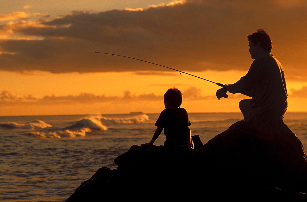 Local family, father and son fishing at sunset with dramatic foreground light