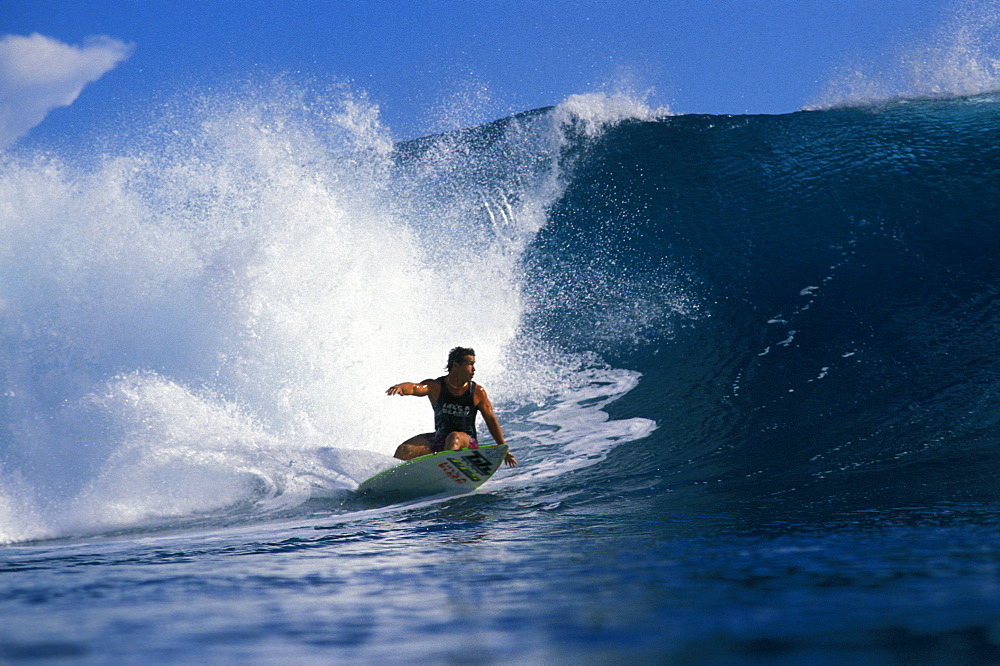 Johnny Boy Gomez, riding a wave, arm extended, turns as wave curls with whitewater