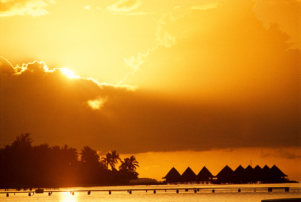 French Polynesia, Bora Bora, Sunset over Hotel Bora Bora huts, golden sun and sky A56C