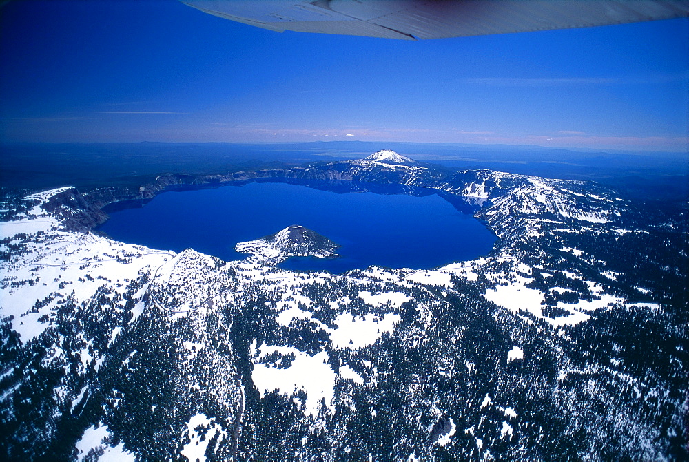 Oregon, Crater Lake, aerial overview, snow scattered, clear blue sky background 