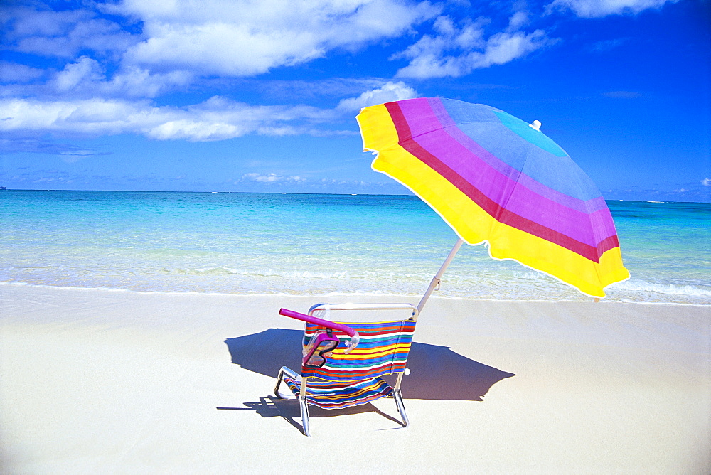 Beach chair and umbrella with snorkel gear, turquoise ocean and blue skies 