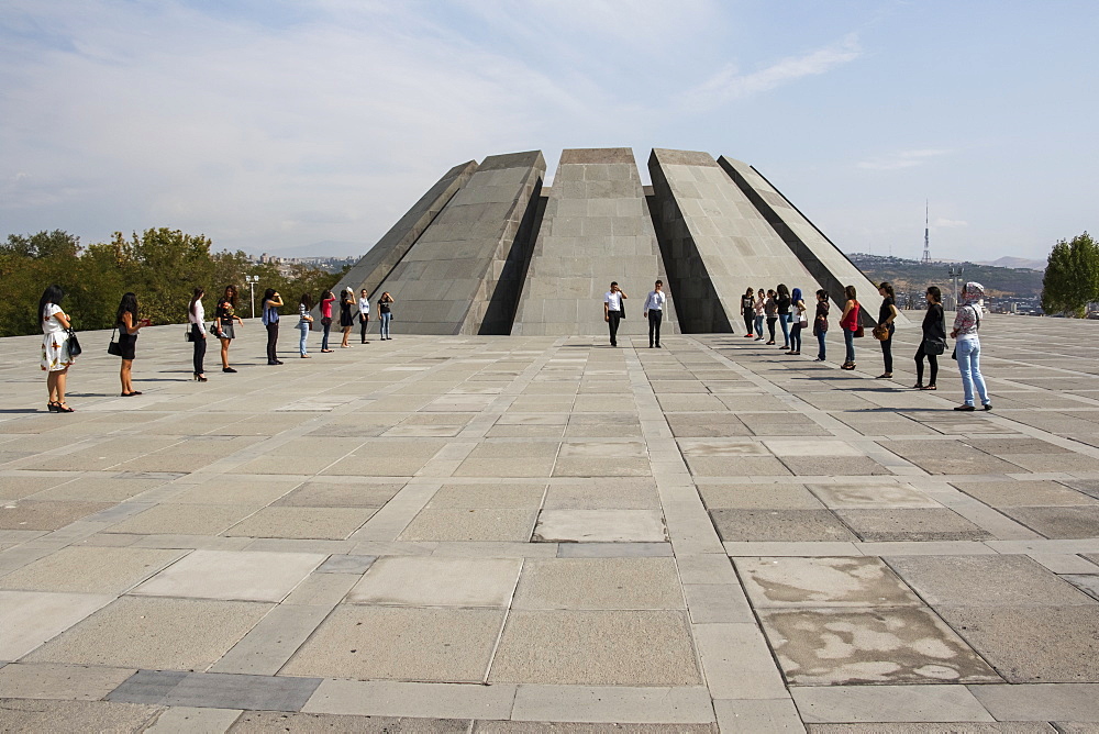 Young people in front of the twelve slabs positioned in a circle, representing the twelve lost provinces in present-day Turkey at the Armenian Genocide memorial complex on Tsitsernakaberd hill, Yerevan, Armenia