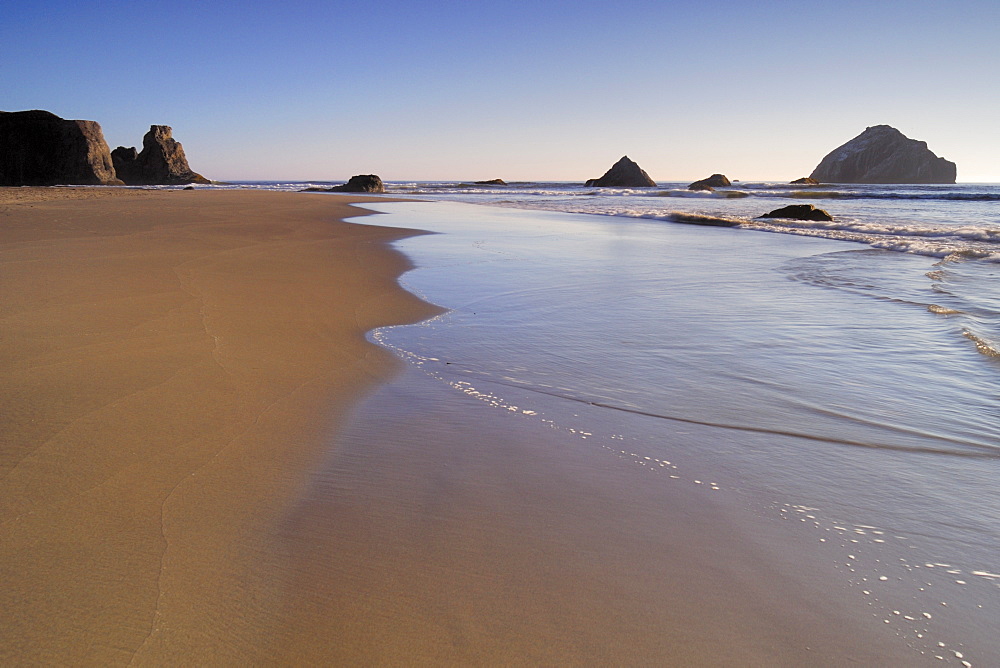 Incoming Tide Patterns In The Sand At Bandon Beach With Seastacks In The Background, Oregon.