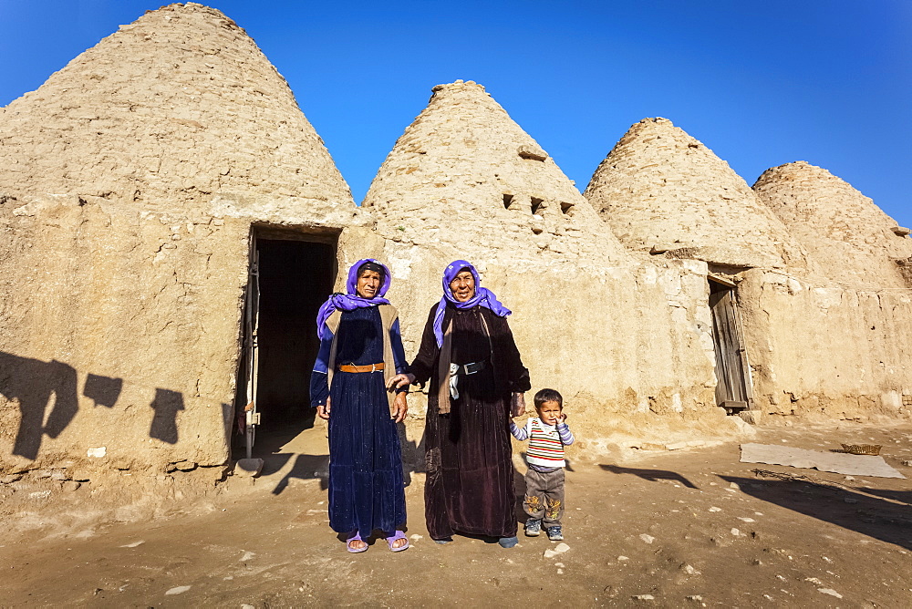 Two women and a child standing outside the doorway of a primitive dwelling, Harran, Turkey