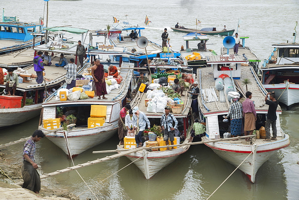 Boats tied up on the Mandalay shore of the Irrawaddy River teaming with activity as they load goods and passengers, Mandalay, Myanmar