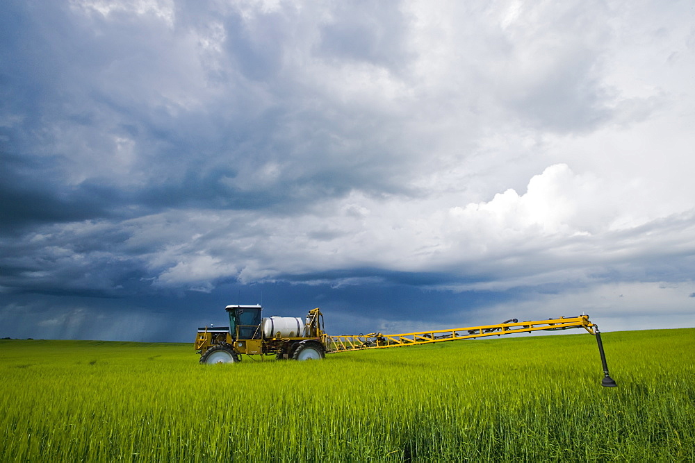 A high clearance sprayer that was applying fungicide on barley sits in a field as a storm approaches, near Holland, Manitoba, Canada