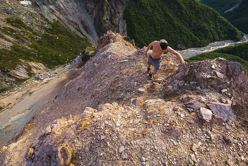 A man climbs a steep ridge above Whistler Creek in the eastern Alaska Range; Alaska, United States of America