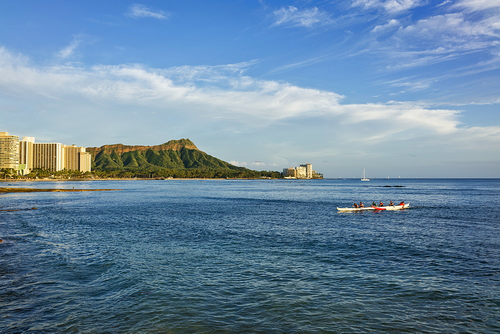 Tourists paddle in an outrigger canoe at Waikiki with Diamond Head in the distance, Waikiki, Oahu, Hawaii, United States of America