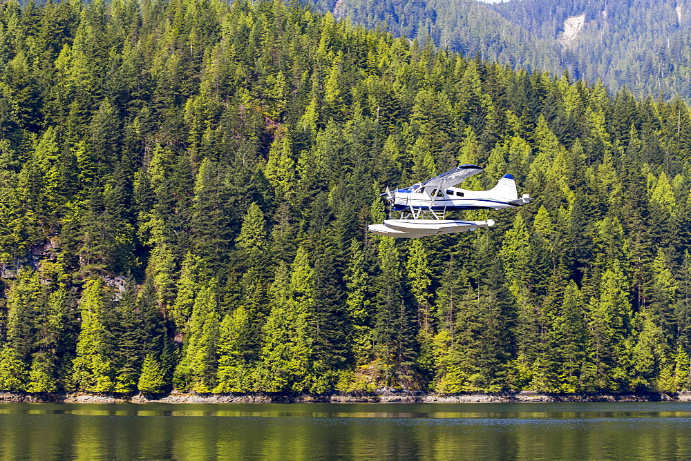 A float plane travels low above the ocean on a scenic tour of the forest and mountains near Vancouver, British Columbia, Canada