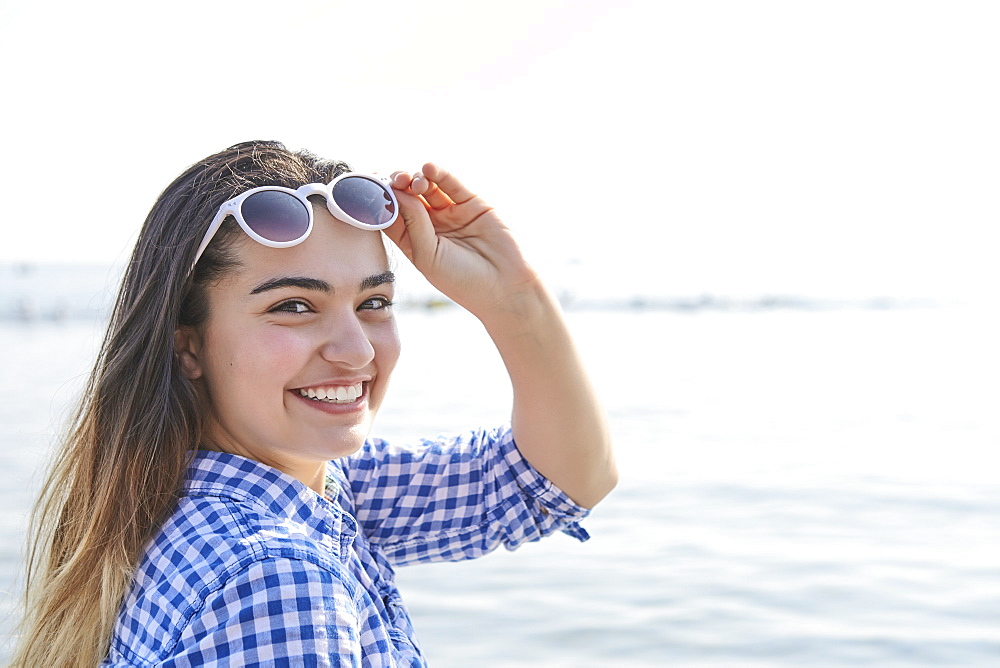 Portrait of a teenage girl at the water's edge at Woodbine Beach in summer, Toronto, Ontario, Canada