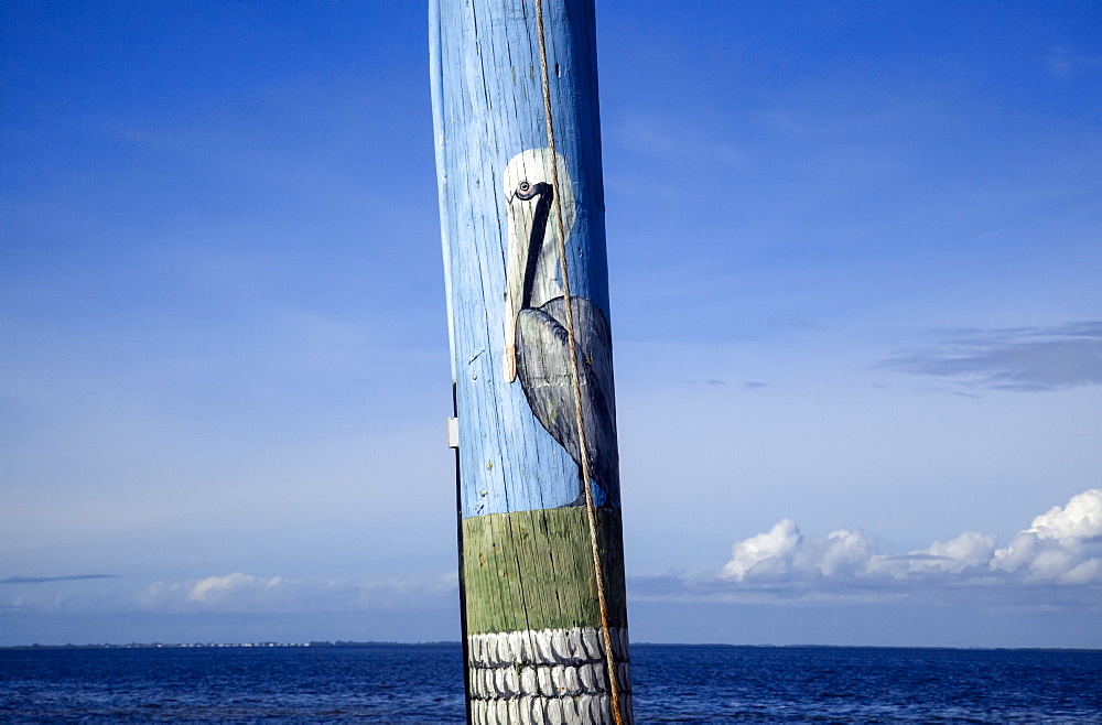 Close-up view of a pelican painted on a telephone pole with ocean and blue sky beyond, Pine Island, Florida, United States of America