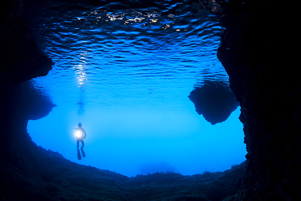 Diver at the entrance to a cavern off the island of Gato, Bohol Sea, Philippines