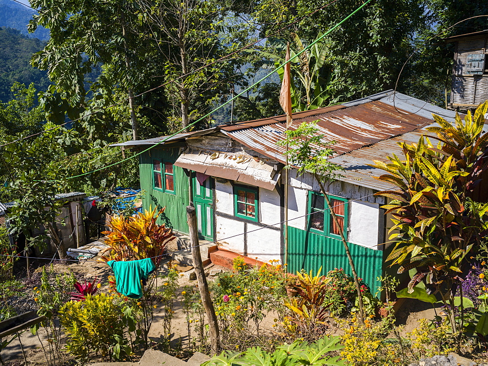 A house with a rusted roof and a clothesline hanging from the trees, West Bengal, India