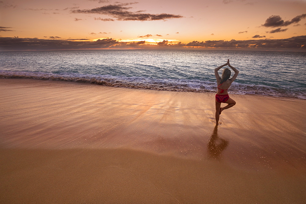 Woman in a yoga pose on the beach at sunset, Molokai, Oahu, Hawaii, United States of America