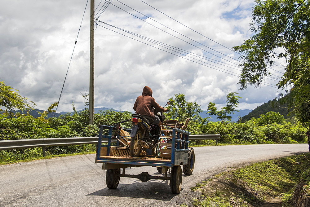 Man driving a tractor carrying a motorcycle near Muang Kham, Xiangkhouang, Laos