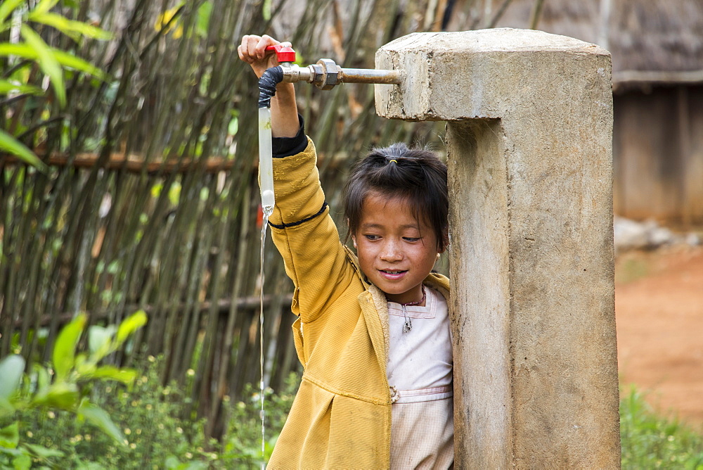 Hmong girl playing with a water tap in Na Kam Peng, also called Bomb Village, Xiangkhouang, Laos