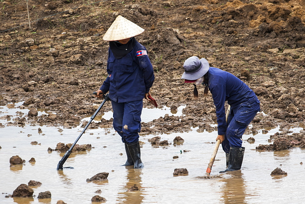 Women using a metal detector while clearing landmines in a field near Phonsavan, Xiangkhouang, Laos