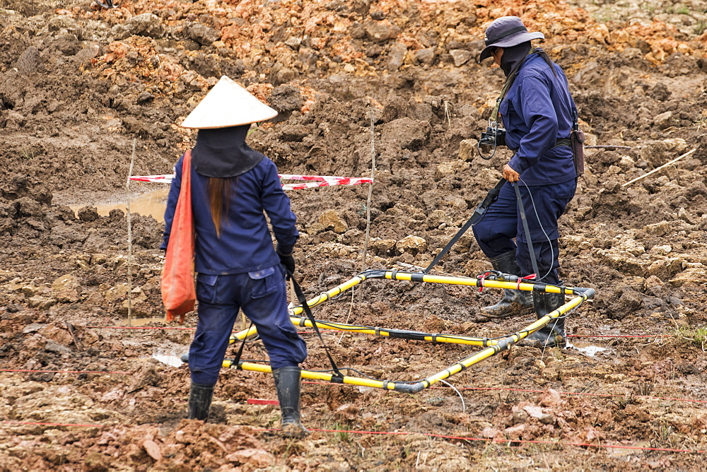 Women using a metal detector while clearing landmines in a field near Phonsavan, Xiangkhouang, Laos