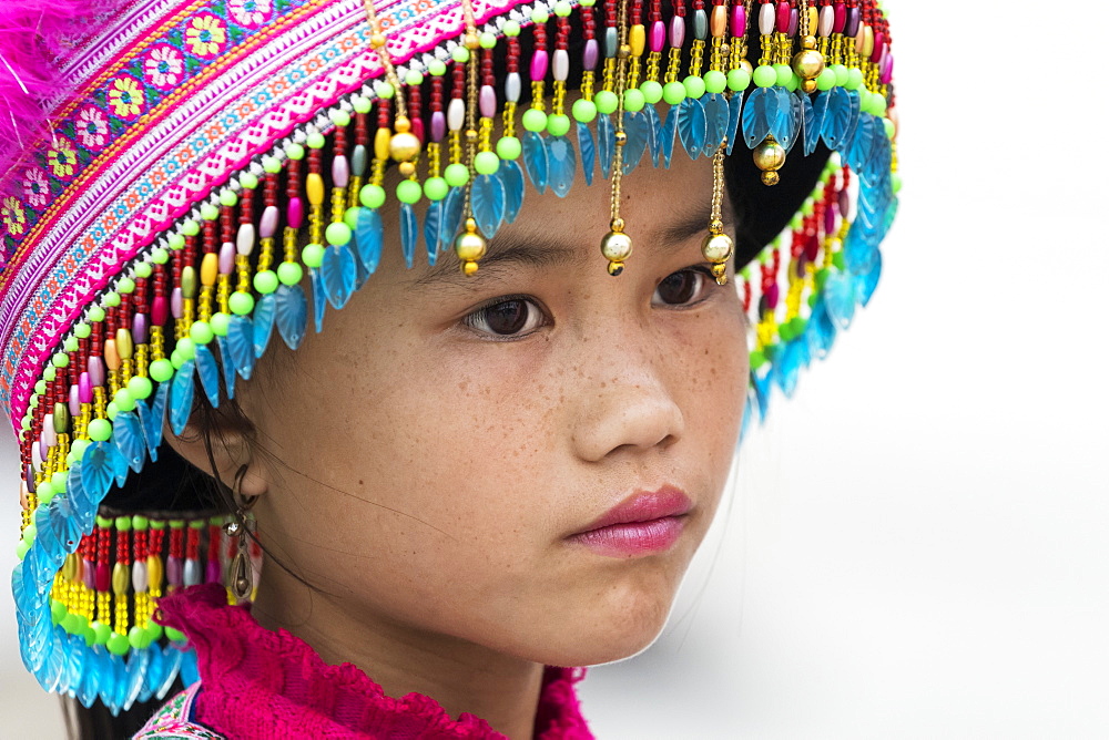 Portrait of a young Hmong girl wearing a colourful, decorative hat, Sapa, Lao Cai, Vietnam