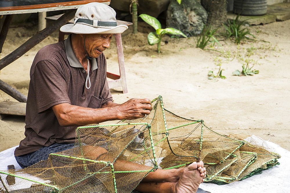 Fisherman sitting and repairing a net, Hoi An Ancient Town, Quang Nam, Vietnam