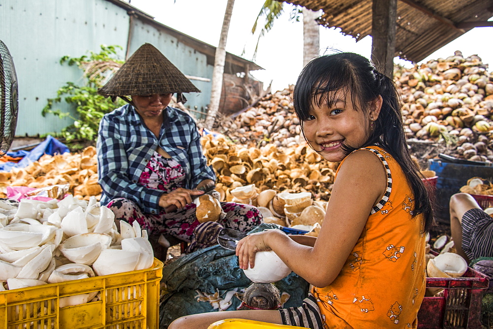 Girl and woman at a coconut processing family owned business in the Mekong Delta, Ben Tre, Vietnam