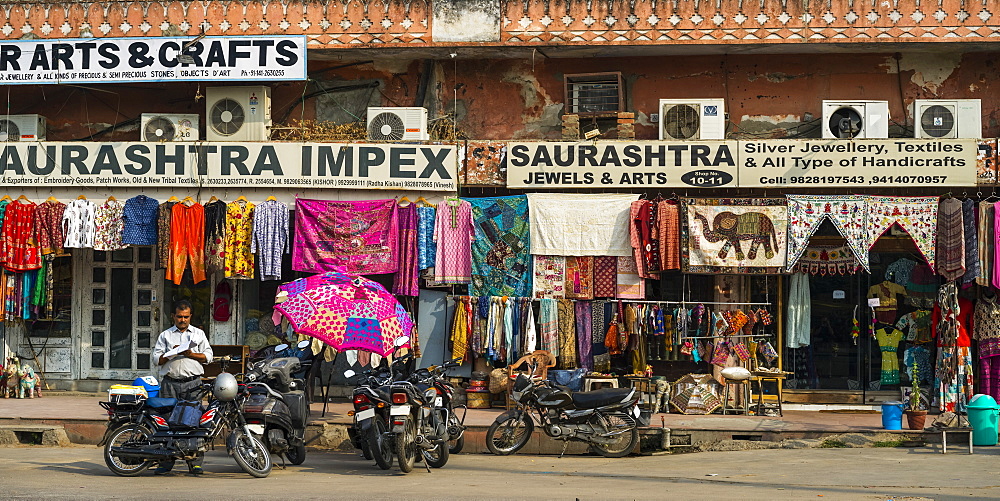 Shops along a street with colourful textiles hanging on display, Jaipur, Rajasthan, India