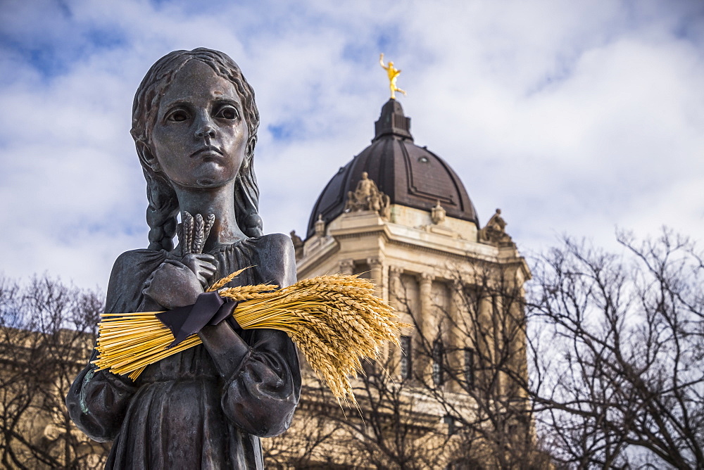 \"Bitter Memories of Childhood” is a memorial statue on the Manitoba Legislative Grounds which pays tribute to the 1932-1933 Ukrainian Famine and Genocide under Soviet ruler Joseph Stalin. The Legislative Building and the Golden Boy are seen in the backgro