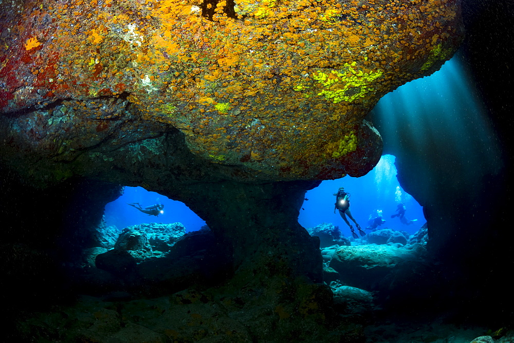 Divers are framed by the twin openings at a dive site known as Skull Cave off the Kona coast of the Big Island, Hawaii, United States of America