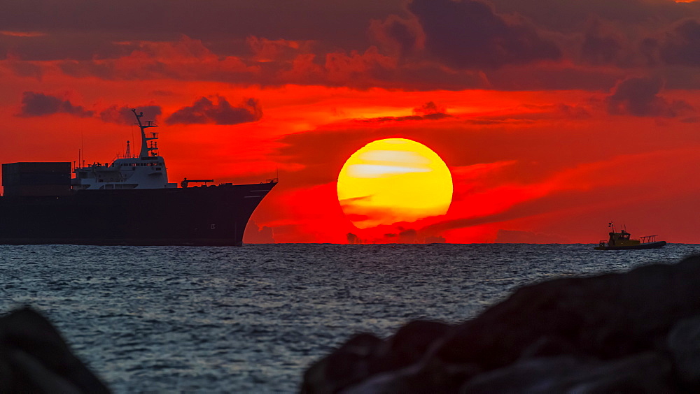 Container ship Horizon Reliance approaching Honolulu at sunset viewed from Magic Island, Ala Monana beach park, Honolulu, Oahu, Hawaii, United States of America